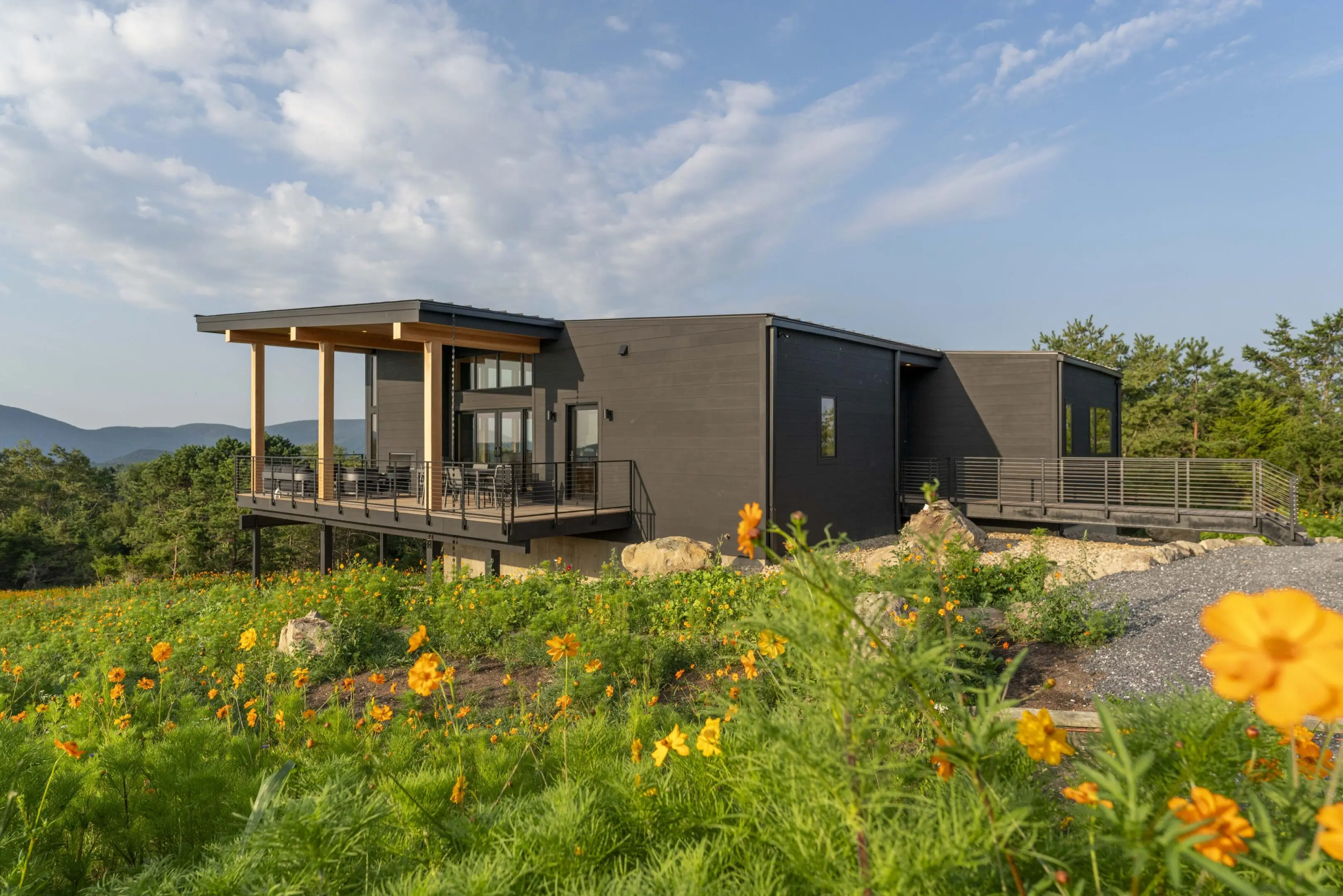 A house with a deck and flowers in the foreground.