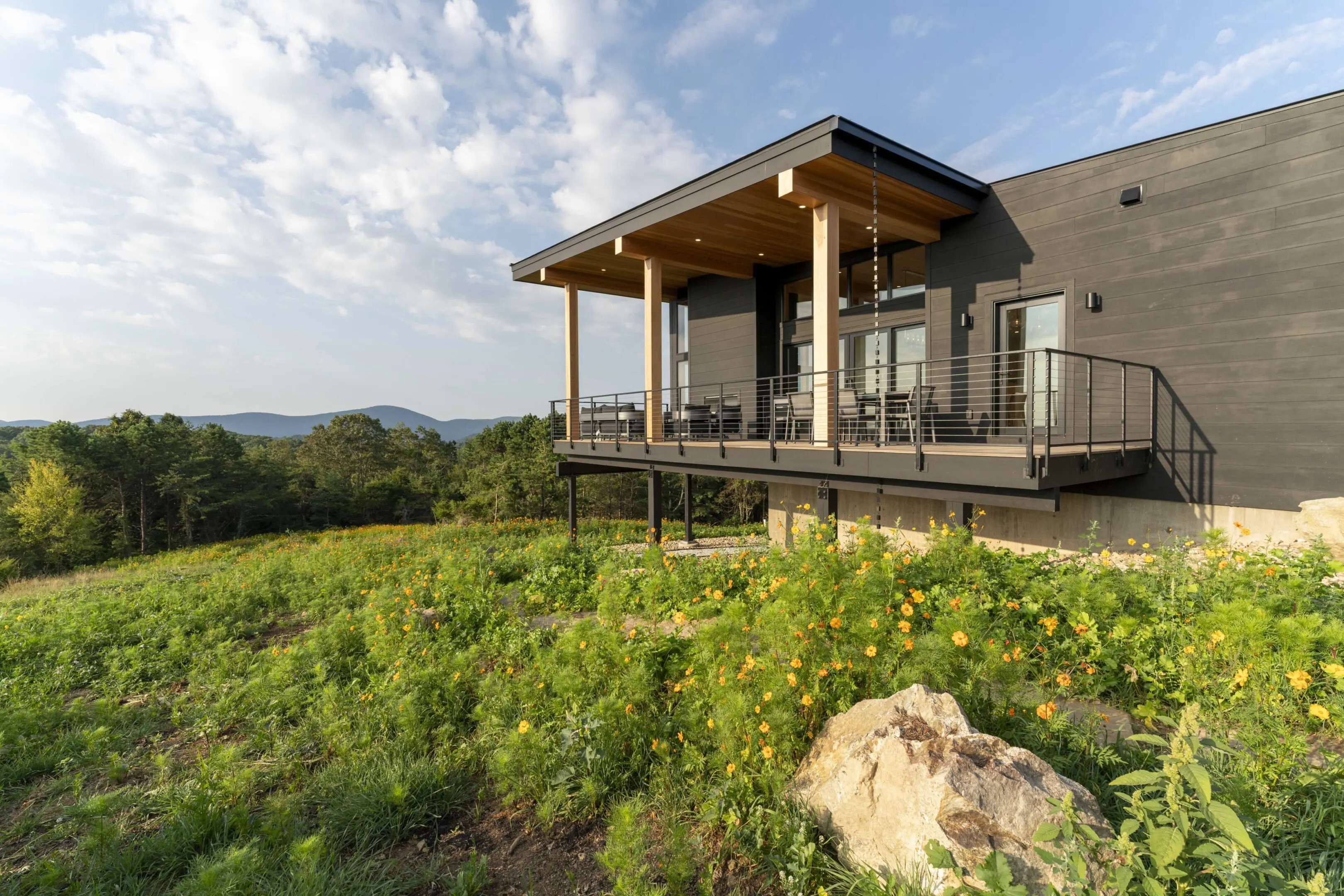 A house with a deck and patio in the middle of a field.