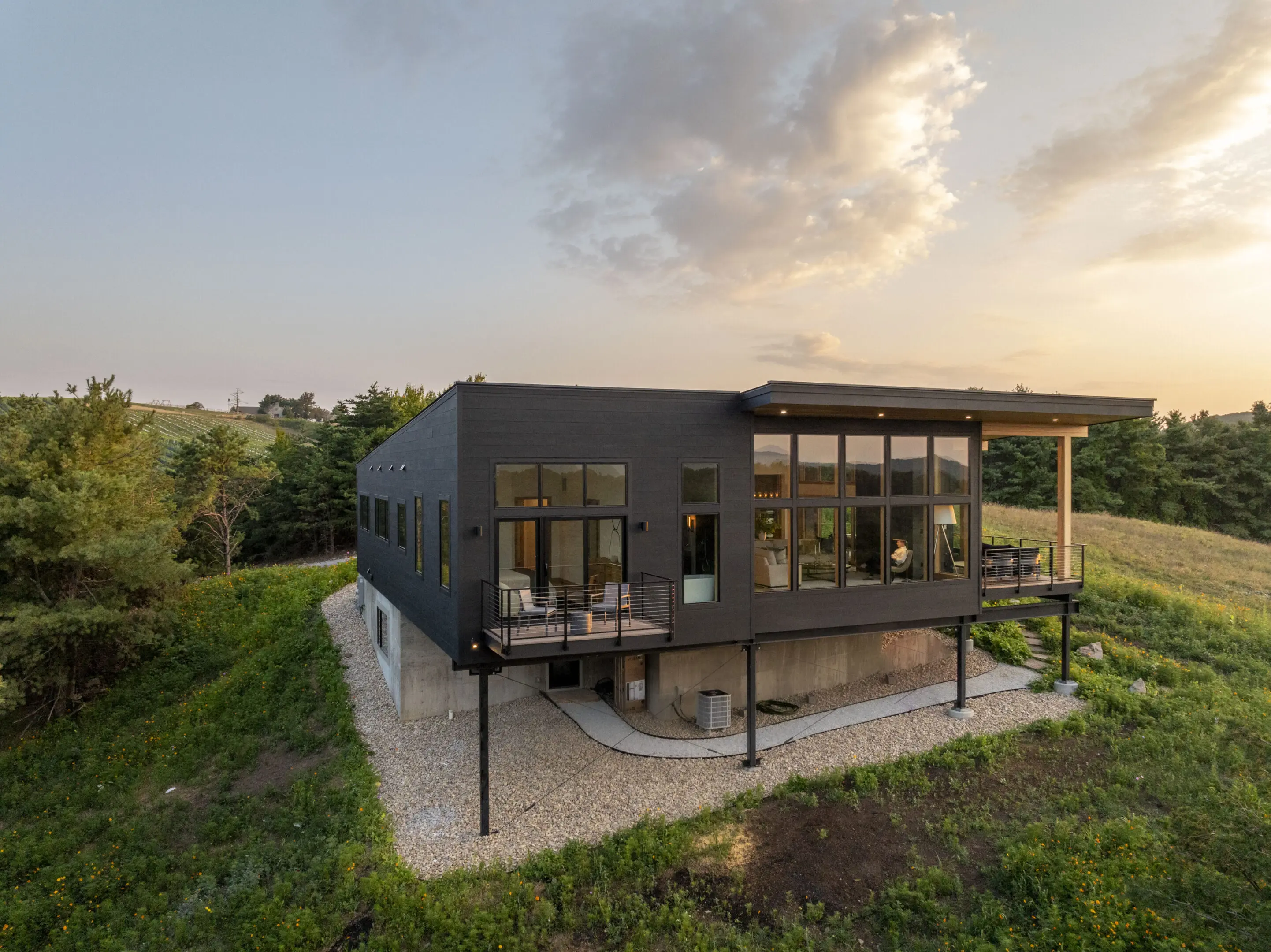 A black house with a green roof and concrete walkway.