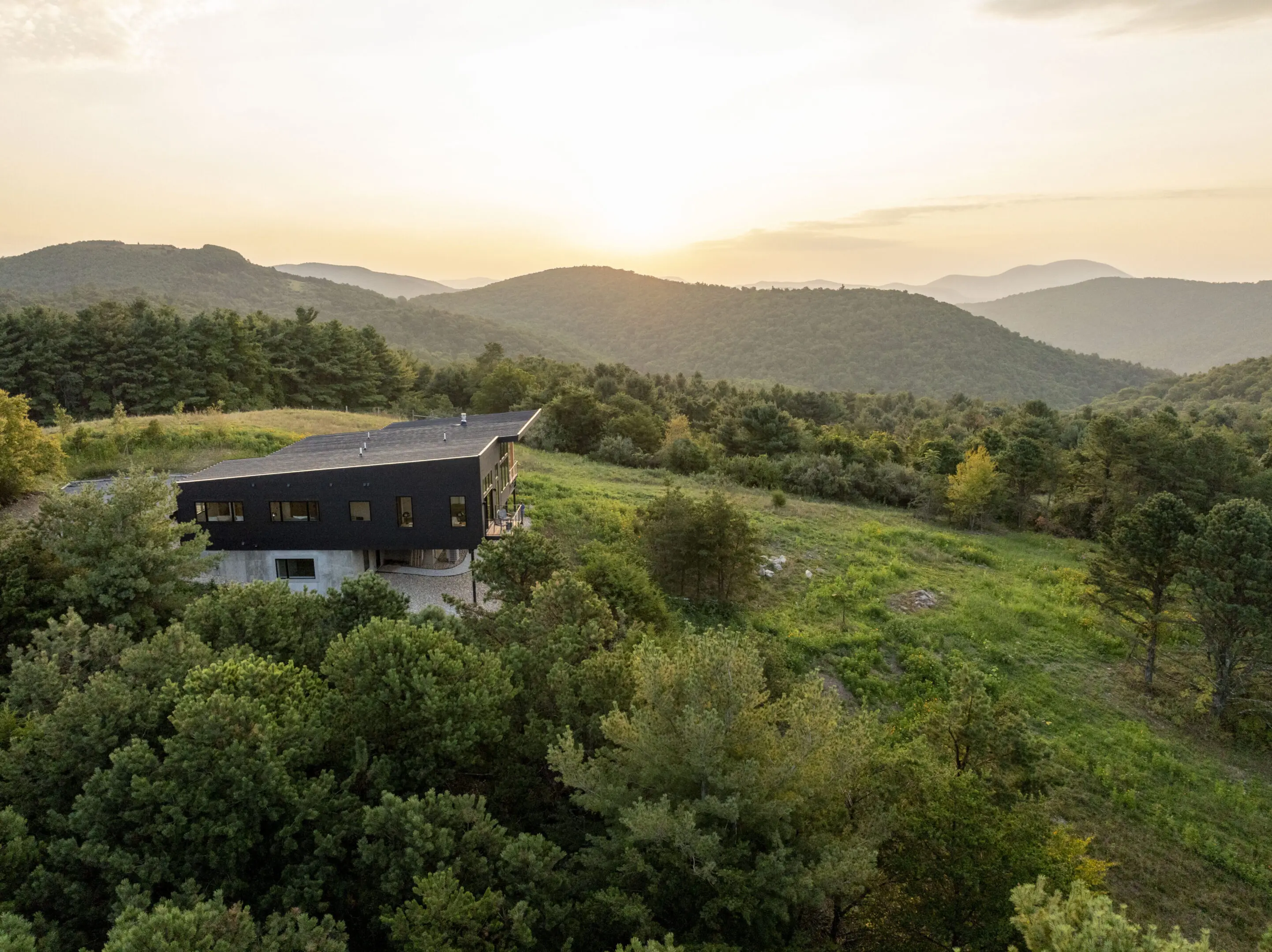 A house sitting on top of a hill with trees in the background.