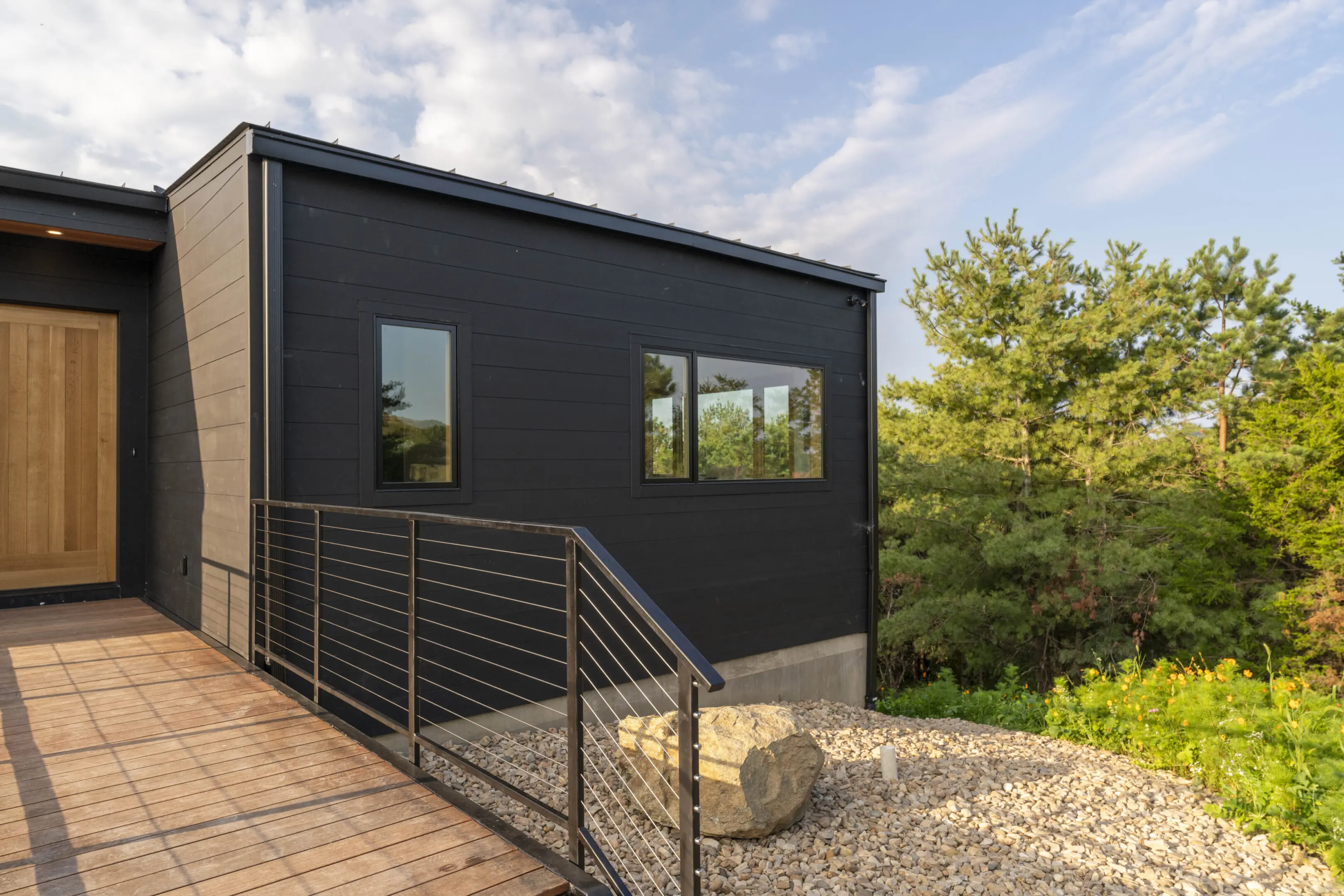 A black house with a metal railing and stone walkway.