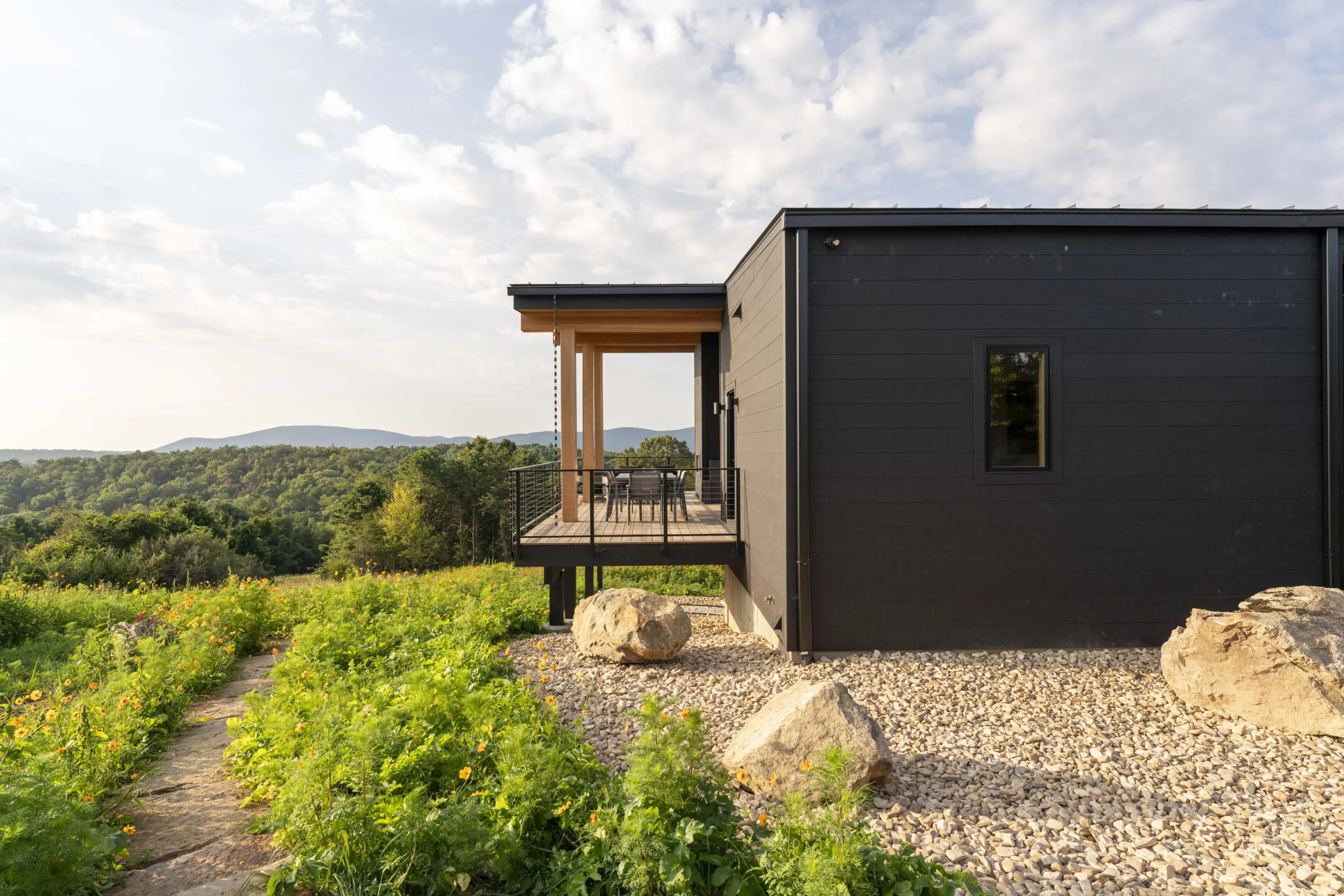 A black house with a deck and patio in the middle of it.