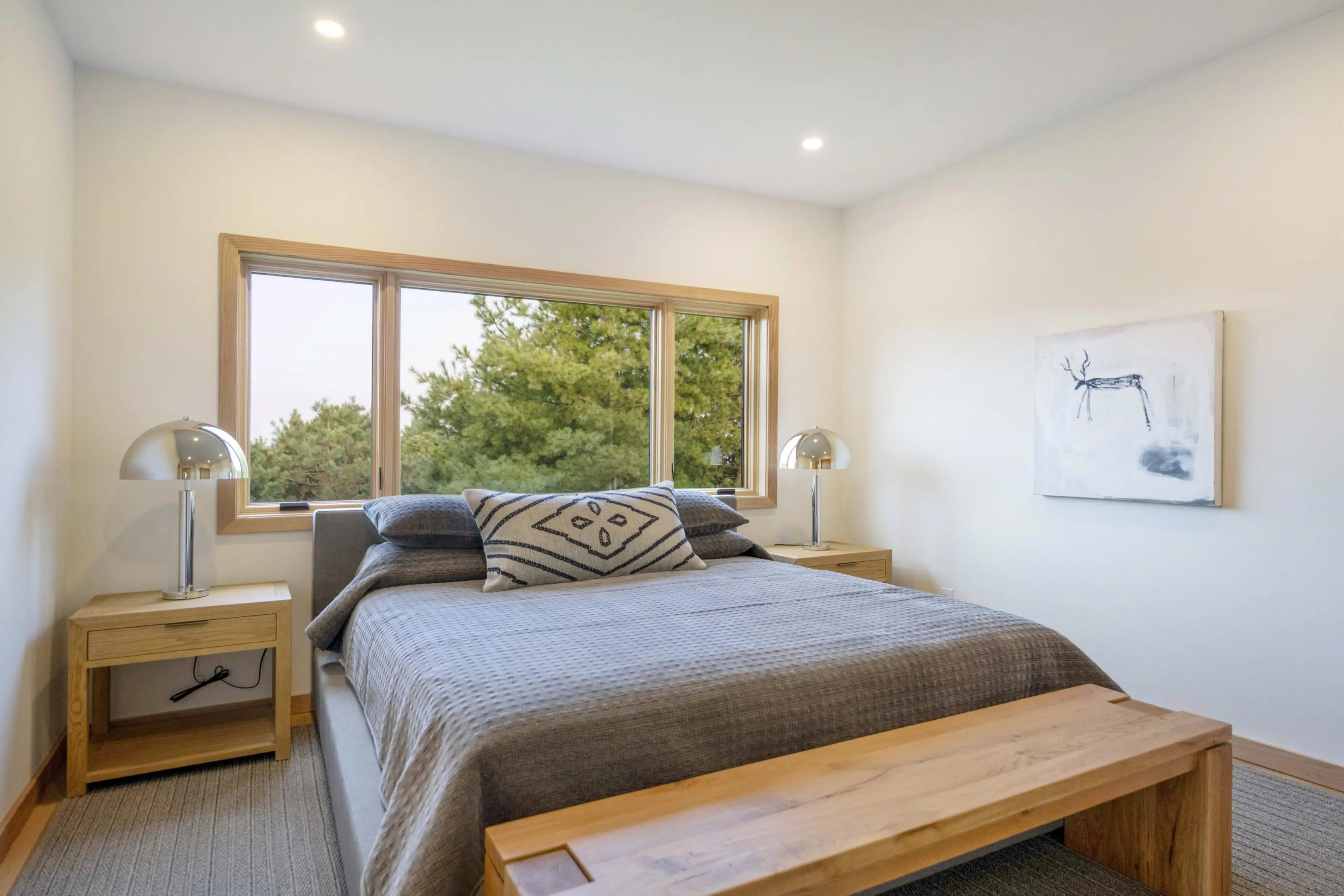 A bedroom with a bed, bench and window.
