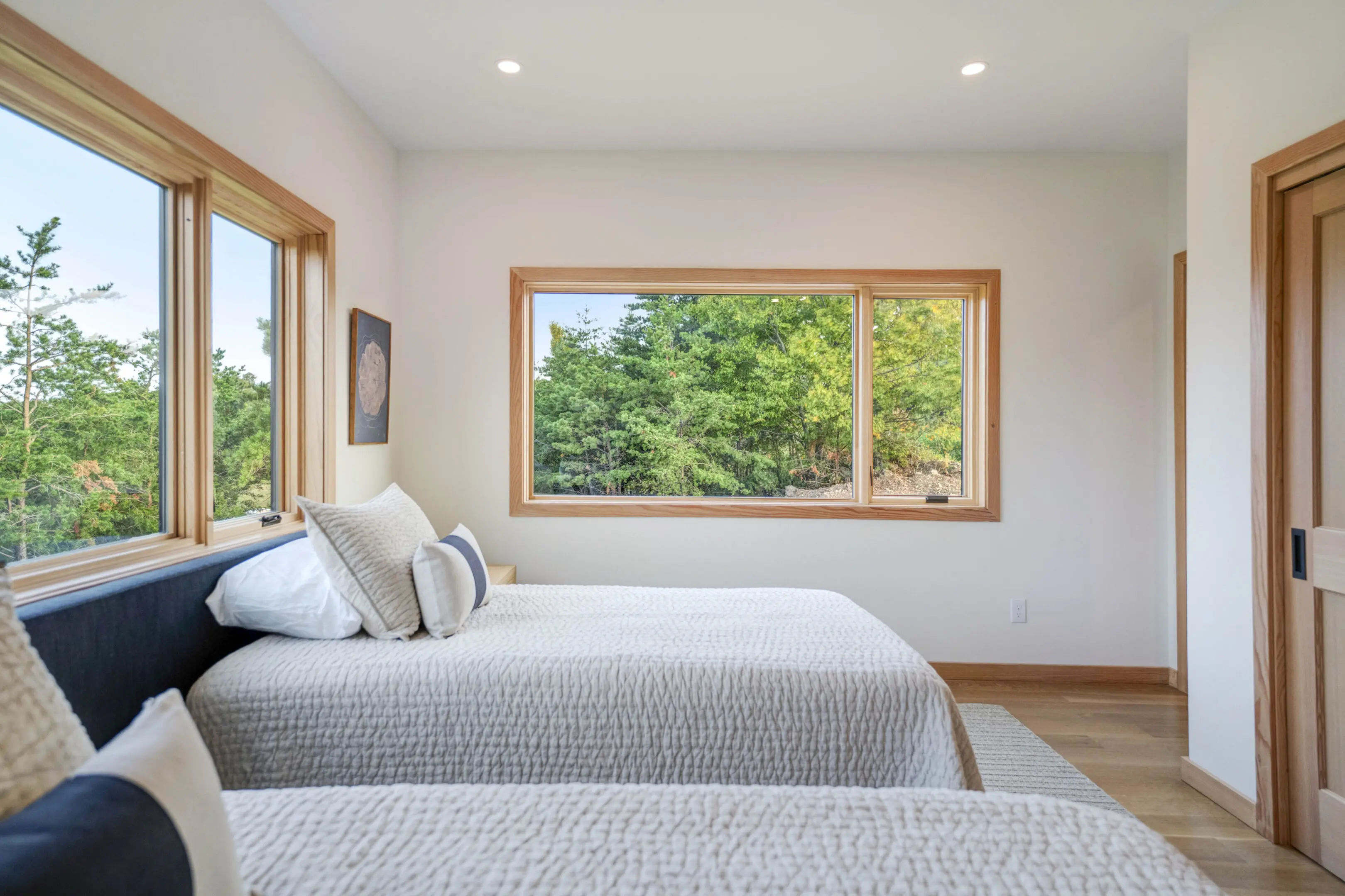 A bedroom with two beds and a large window.