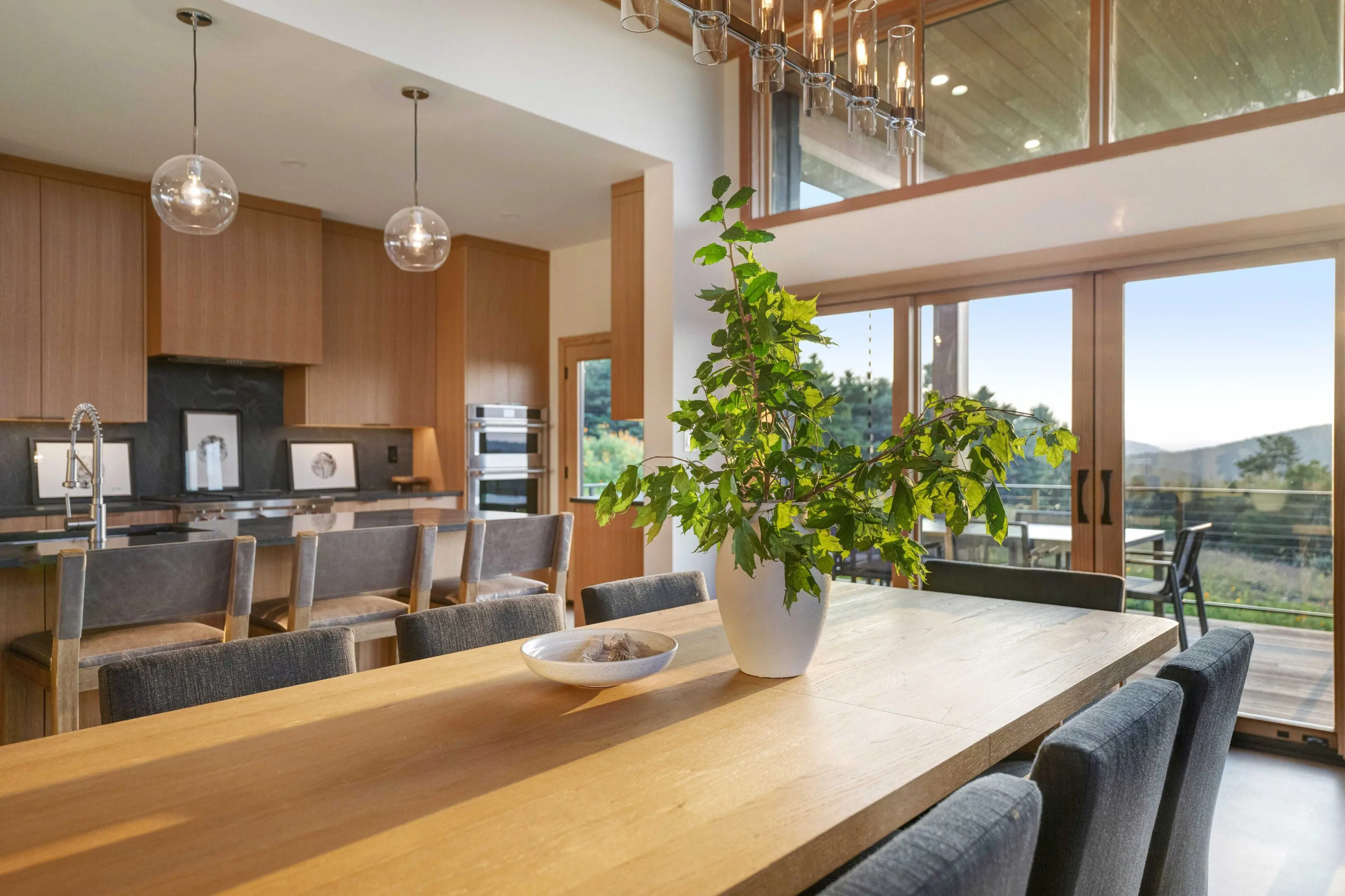 A dining room table with a plant in the middle of it.