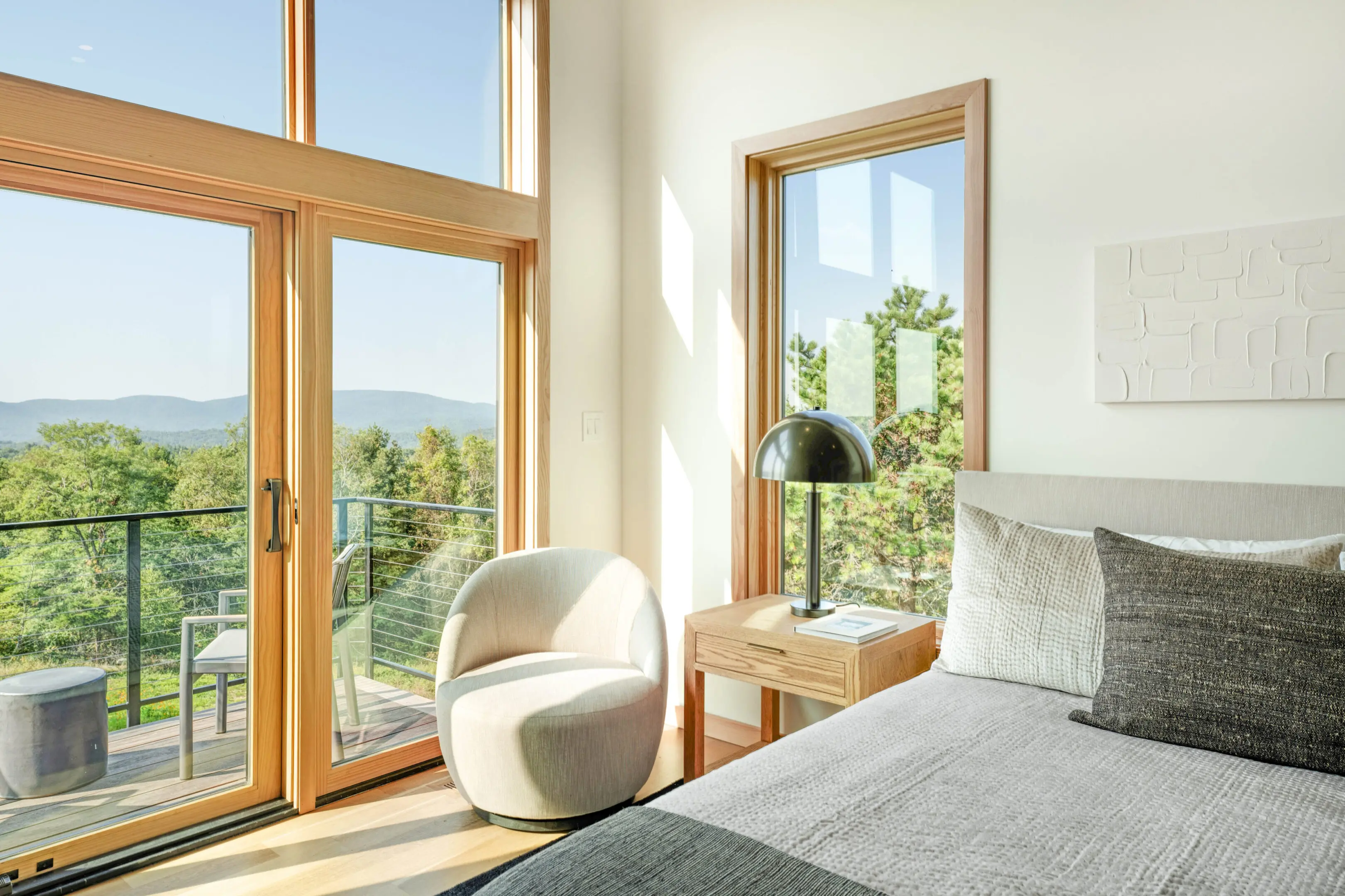 A bedroom with large windows and a view of the mountains.