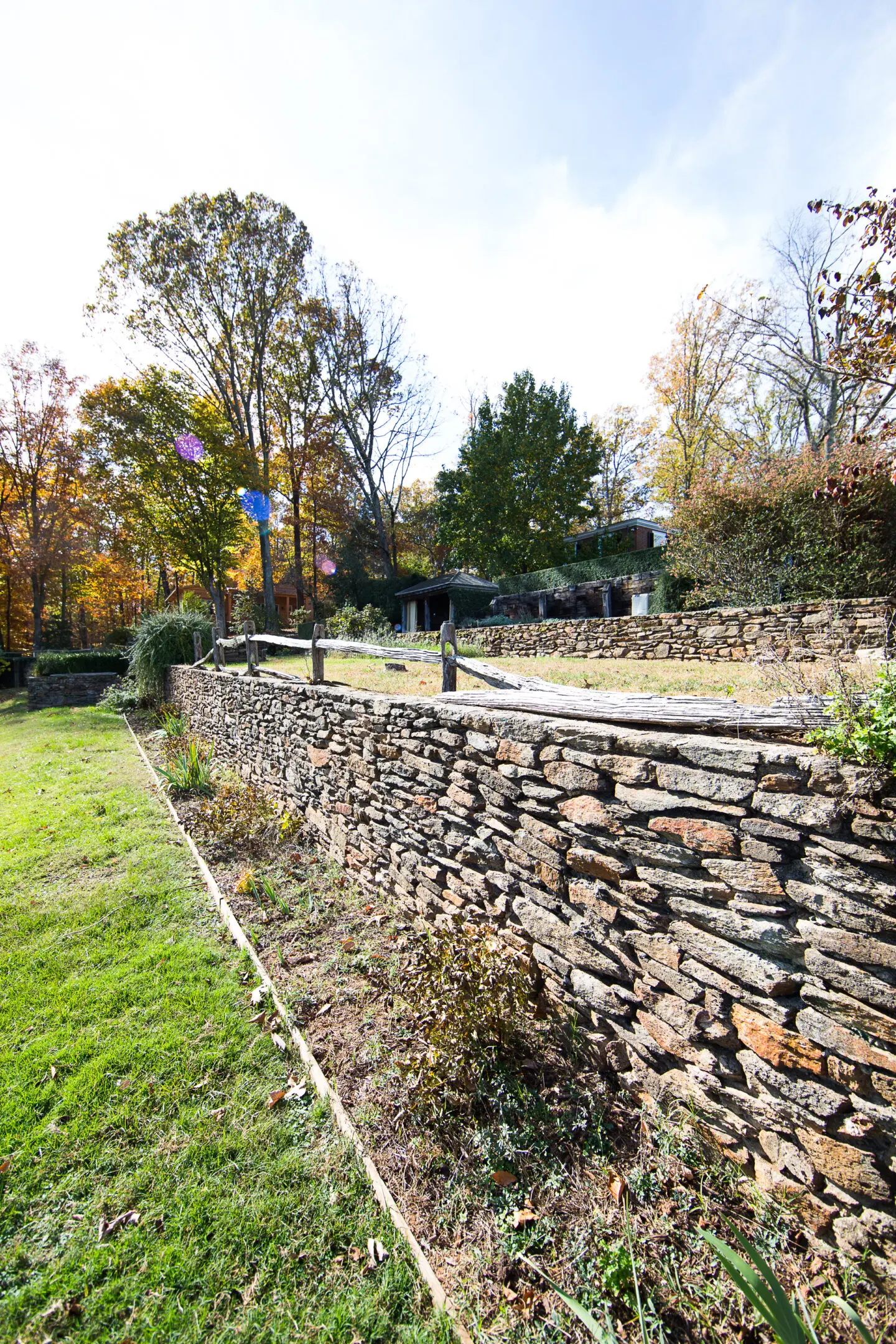 A stone wall in the middle of a yard.
