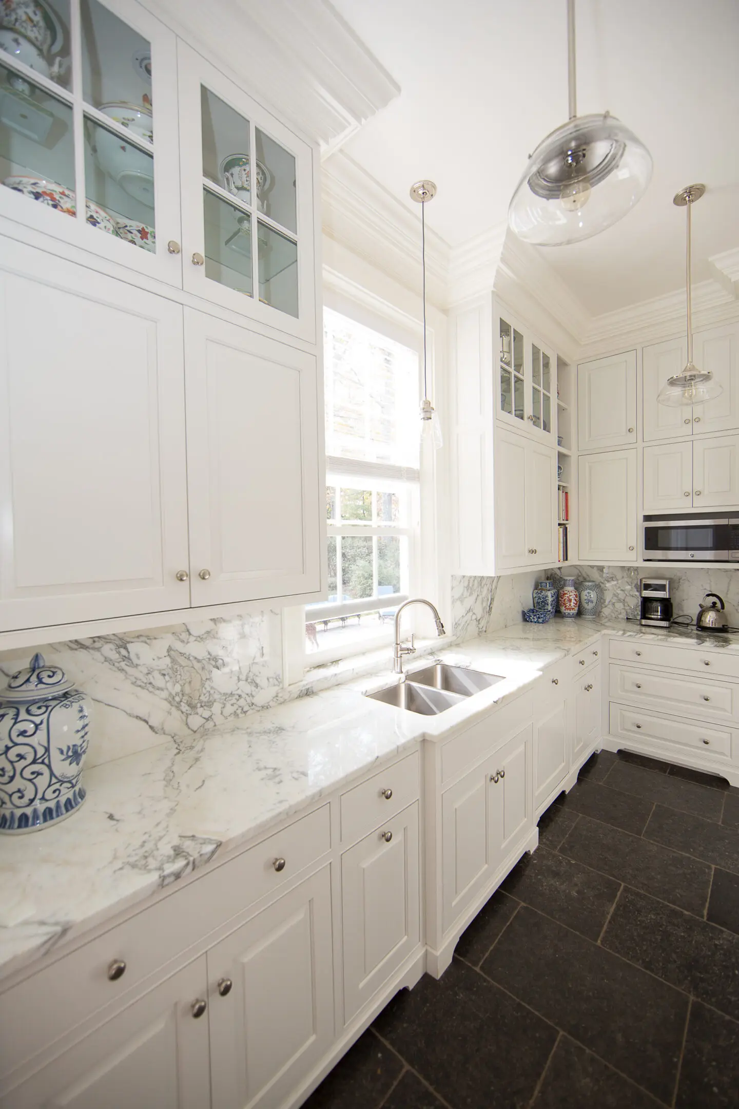 A kitchen with white cabinets and marble countertops.