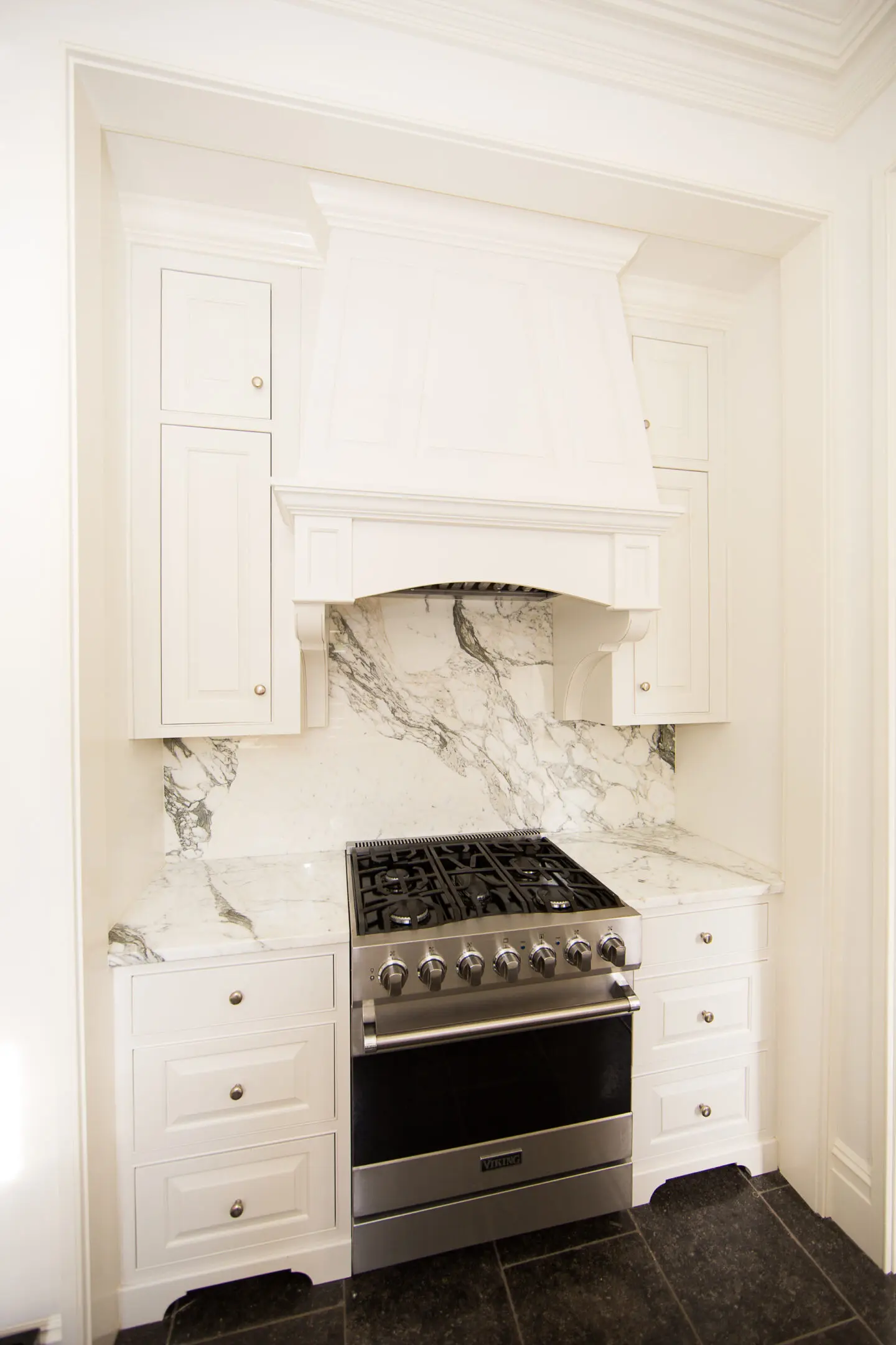 A stove and cabinets in a kitchen with white walls.