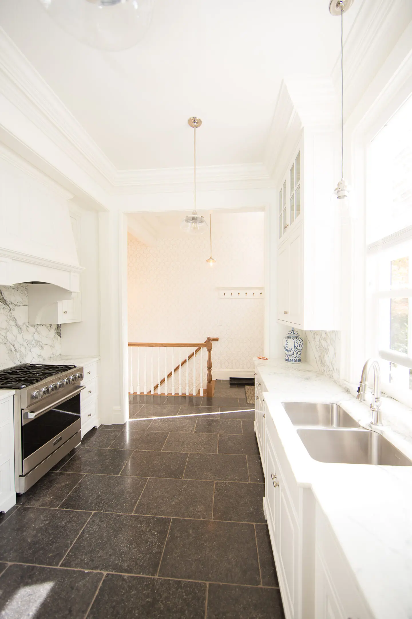 A kitchen with white walls and tile floors.