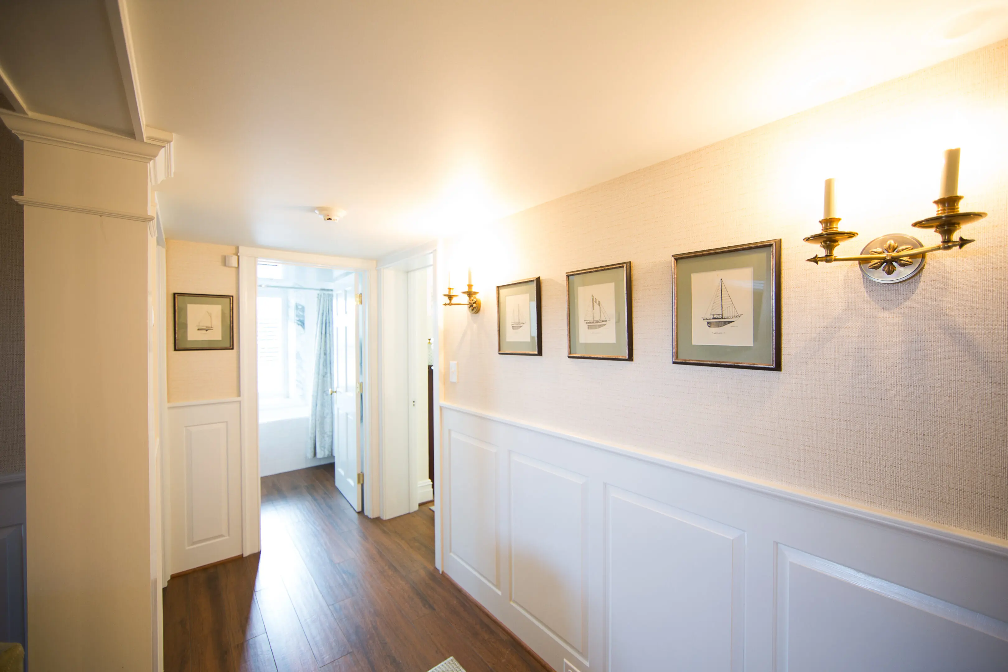 A hallway with white walls and wooden floors.