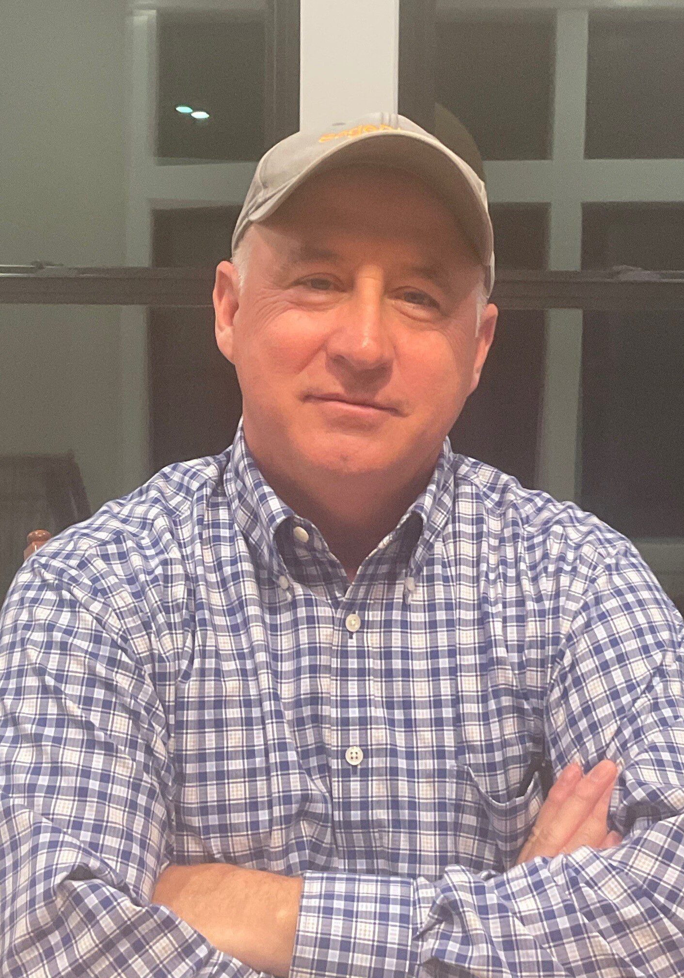 67f848ebddb5e_Photo of Doug Lowe A man in plaid shirt and hat with arms crossed.